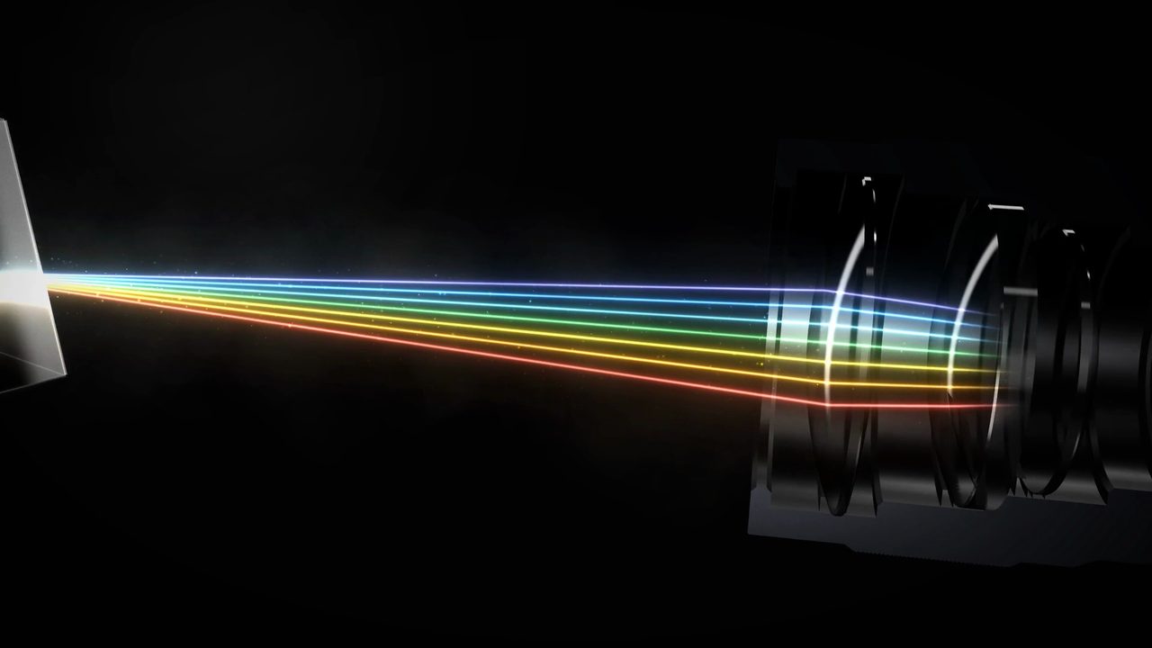 A spectrum of coloured light beams entering a cut-away camera lens